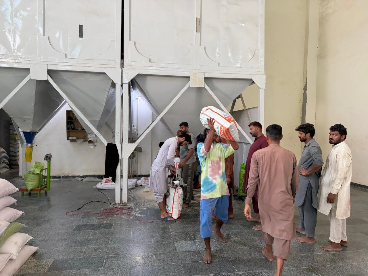 Bagging area with rice sacks and people working at Eagle Rice Mills